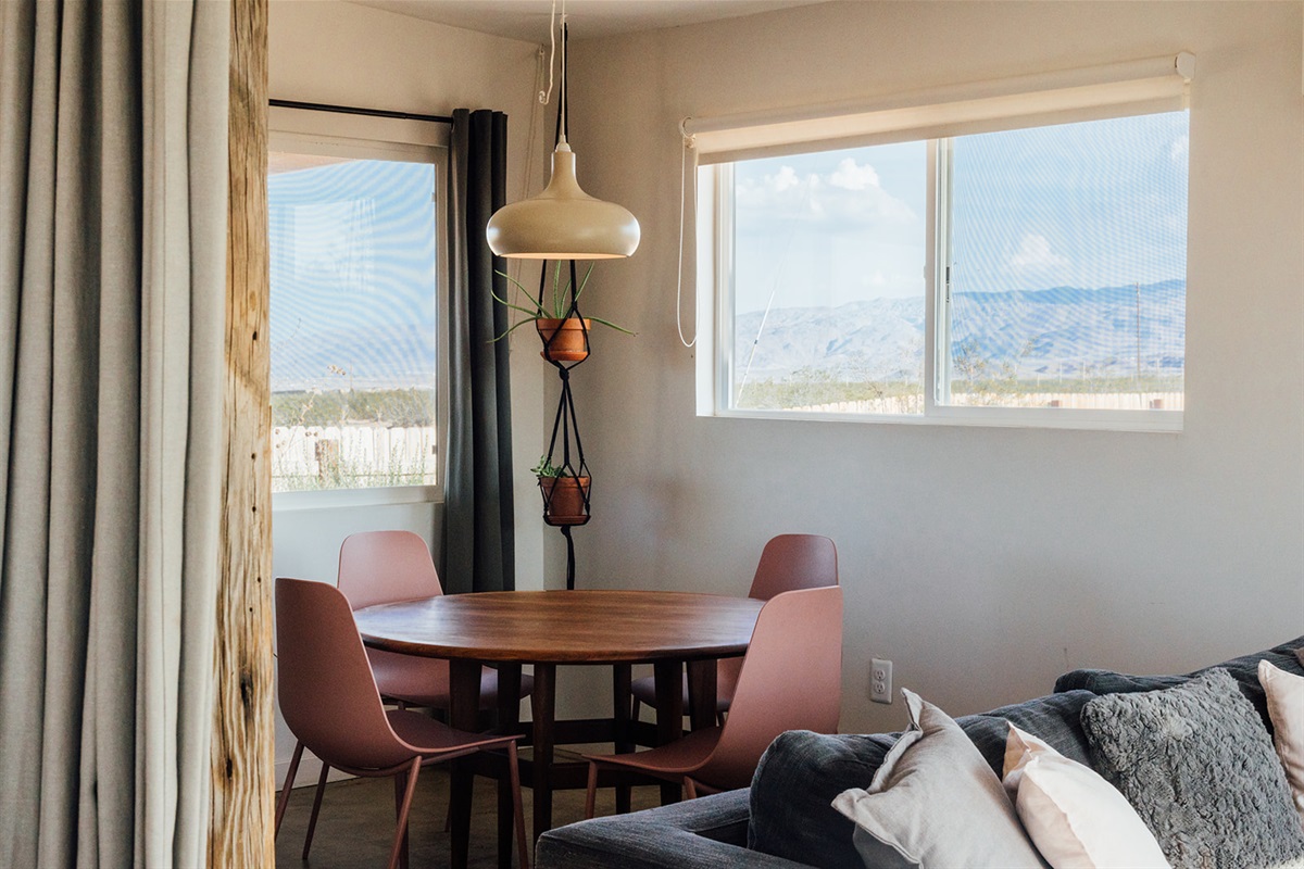 Bright dining area with modern table and chairs, warm natural light, and desert views — perfect for enjoying meals together.