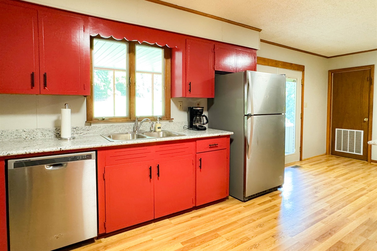Drip coffee maker, large refrigerator, dishwasher, and dinnerware.