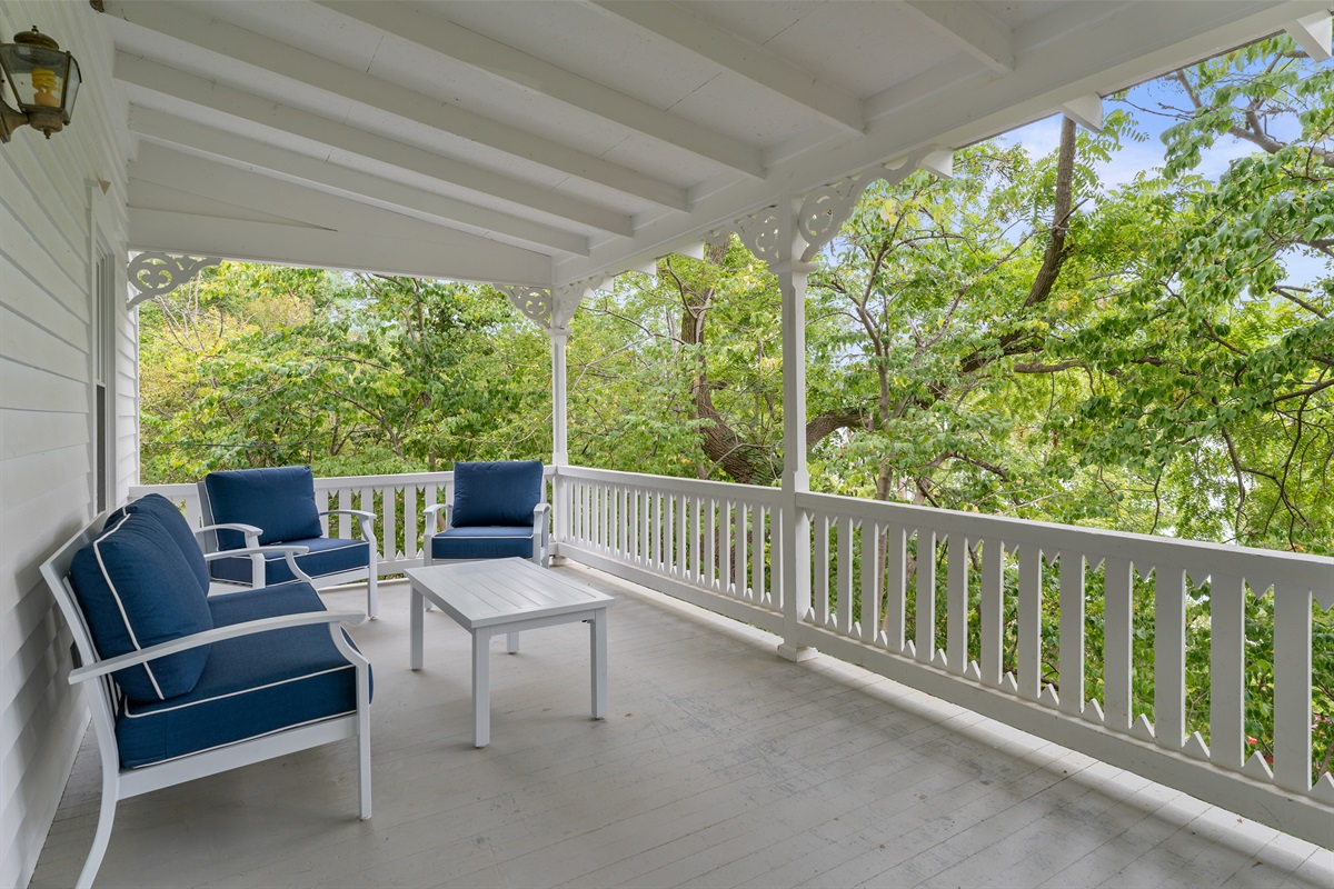 Charming covered porch surrounded by trees, perfect for relaxing with morning coffee or outdoor dining.
