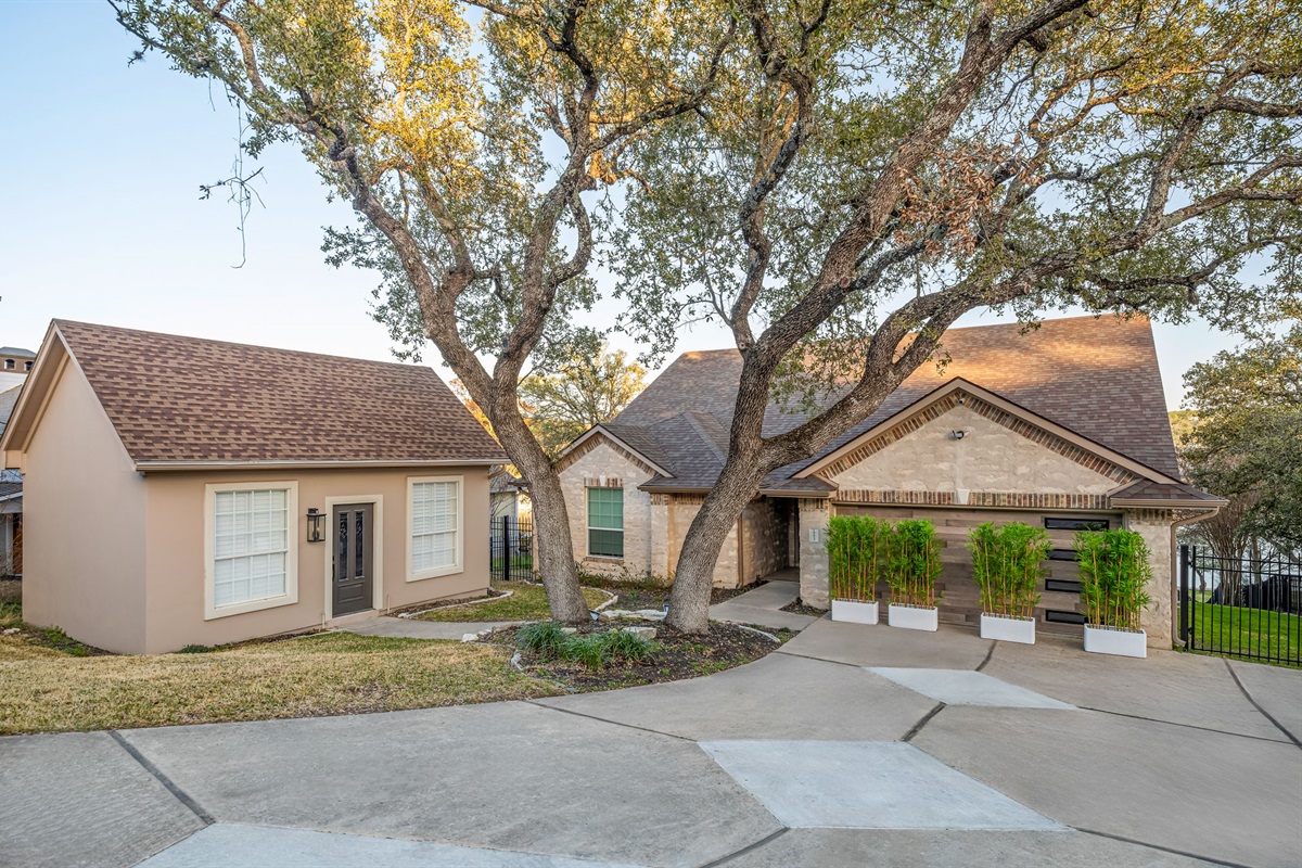 Welcoming front exterior with spacious driveway and mature trees.