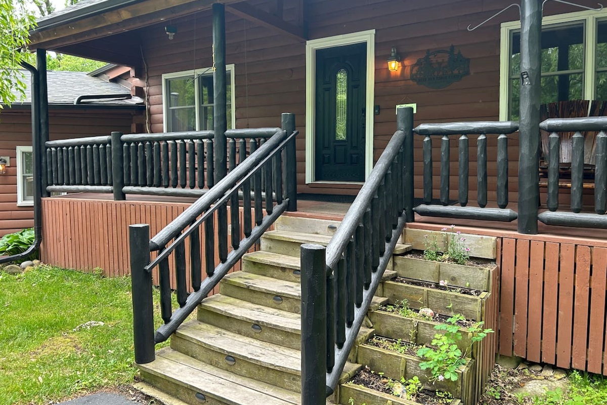 Stairs leading to front porch of log cabin.