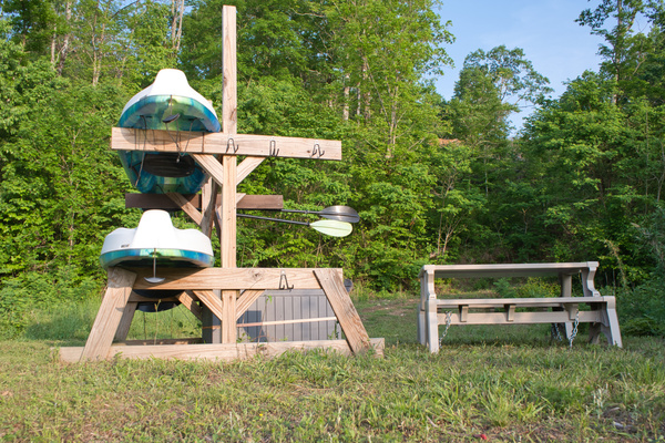 Guest-use kayaks are stored on the rack near the water, with paddles, life jackets and outdoor seating nearby.