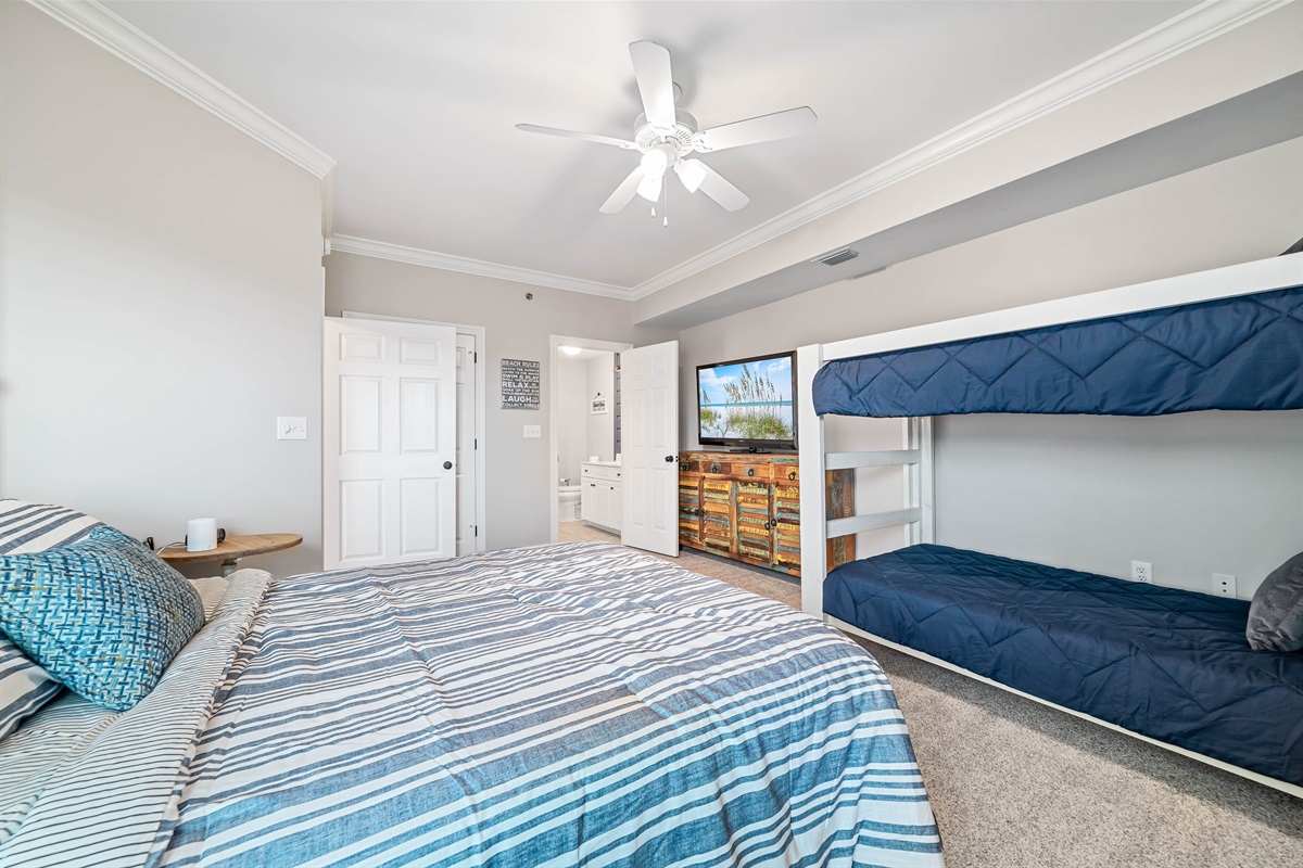 A charming bedroom featuring a comfortable queen bed and bunk bed, perfect for sharing and relaxation after a day of coastal adventures.