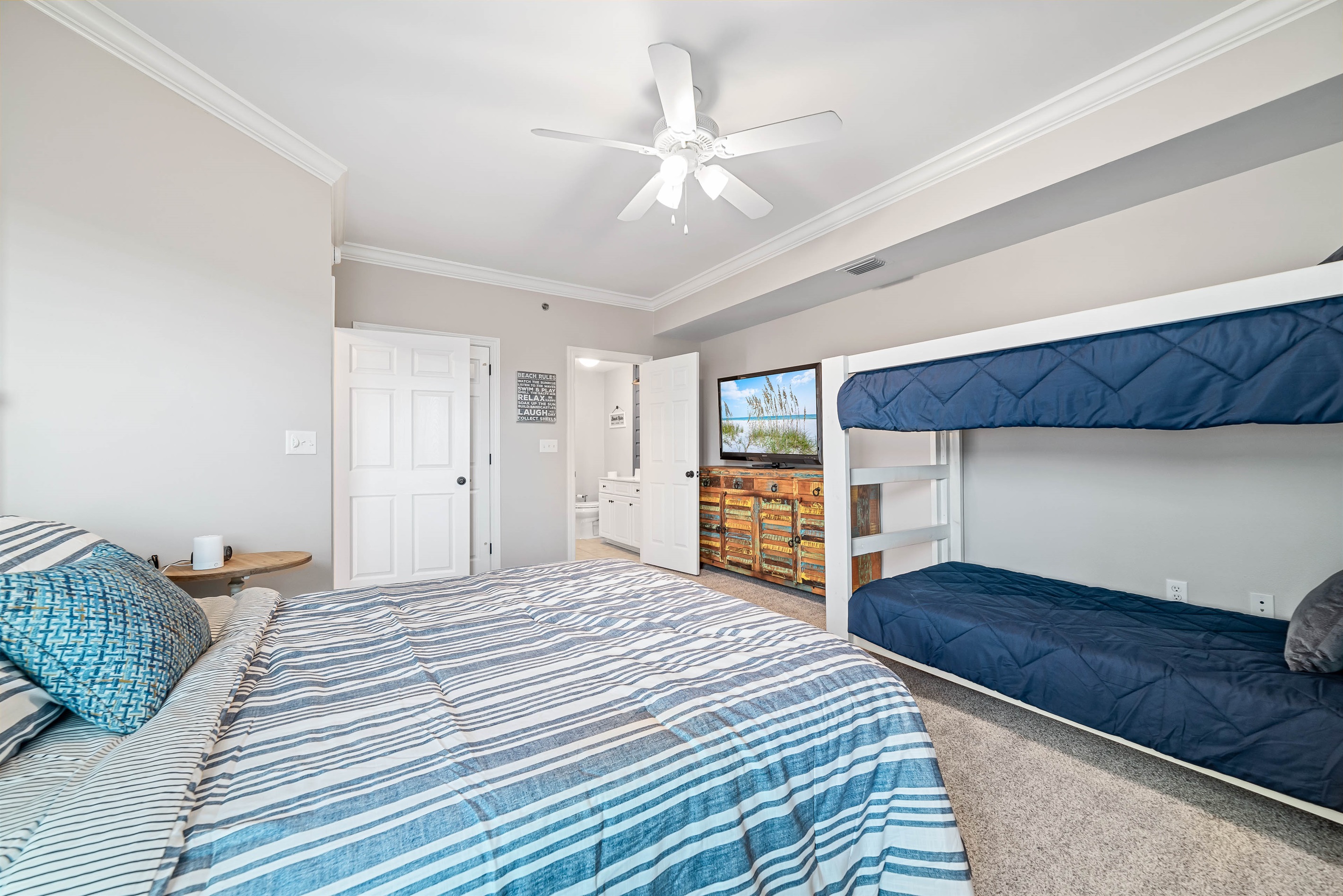 A charming bedroom featuring a comfortable queen bed and bunk bed, perfect for sharing and relaxation after a day of coastal adventures.