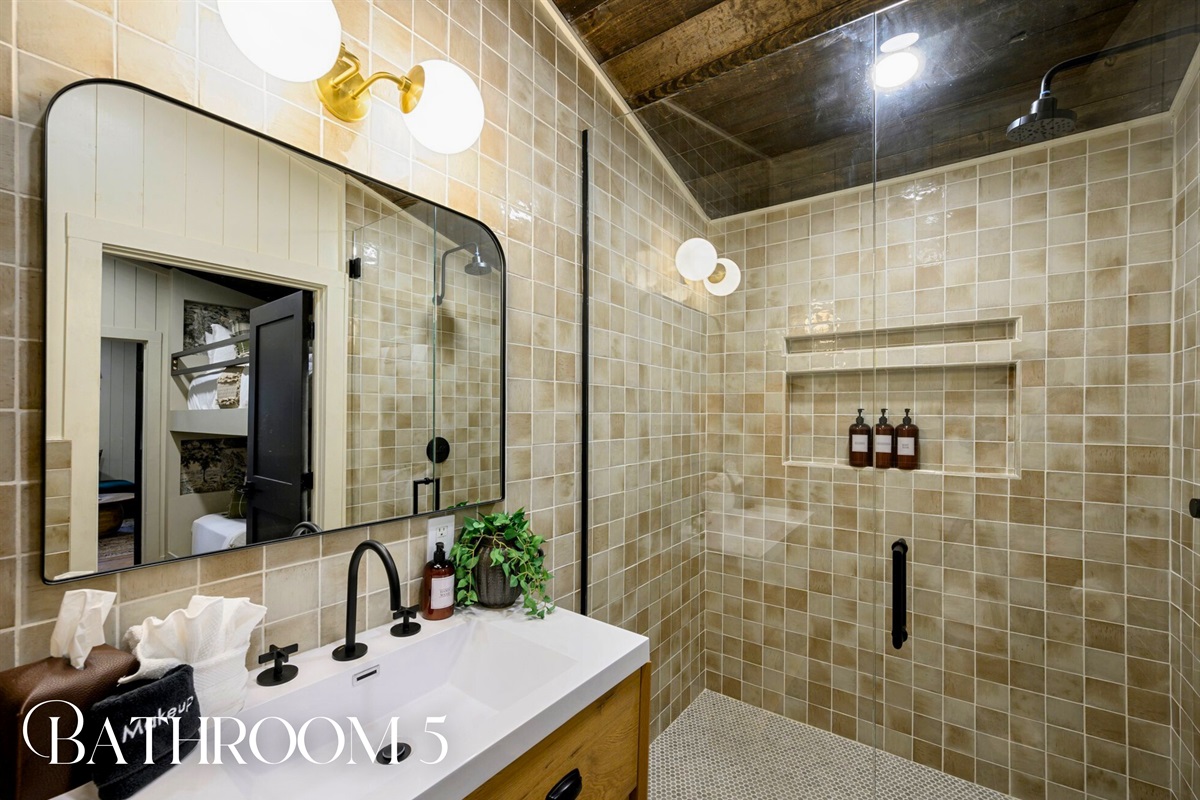 Another bathroom is outfitted with warm tilework, soft lighting, and a roomy walk-in shower.