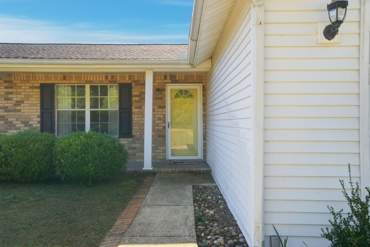 Welcoming front entry with a glass storm door and classic brick accents.