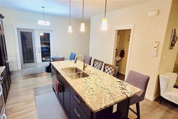 Stylish kitchen with granite island, bar seating, and patio-access dining nook.