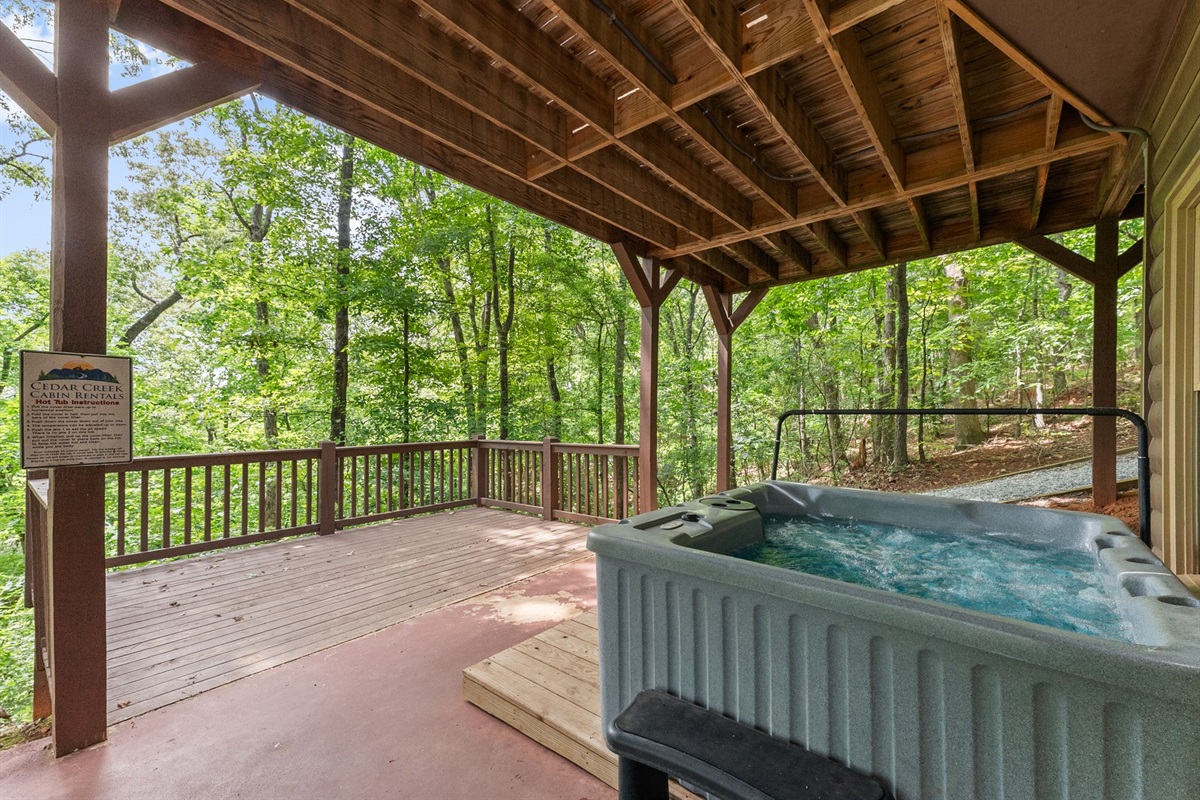 Covered hot tub surrounded by peaceful woodland scenery.