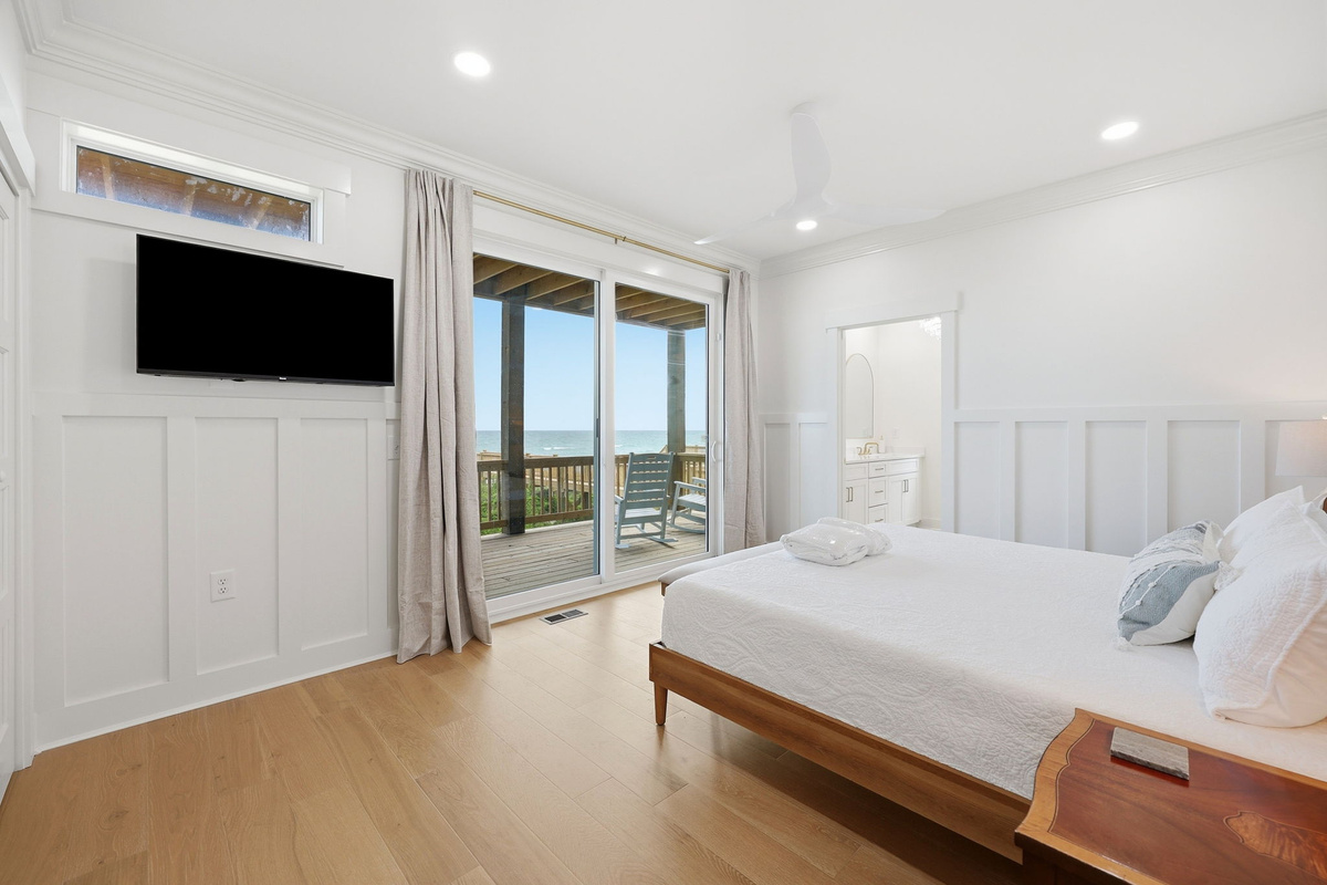 Second-floor king master bedroom with oceanfront deck access and natural light