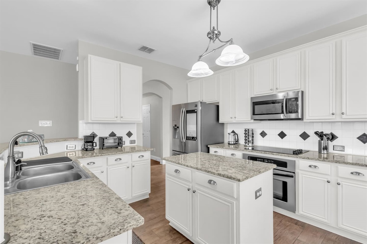 Fully equipped kitchen with electric stove, microwave, dishwasher, refrigerator, freezer, and all cooking basics needed for easy home-cooked meals.