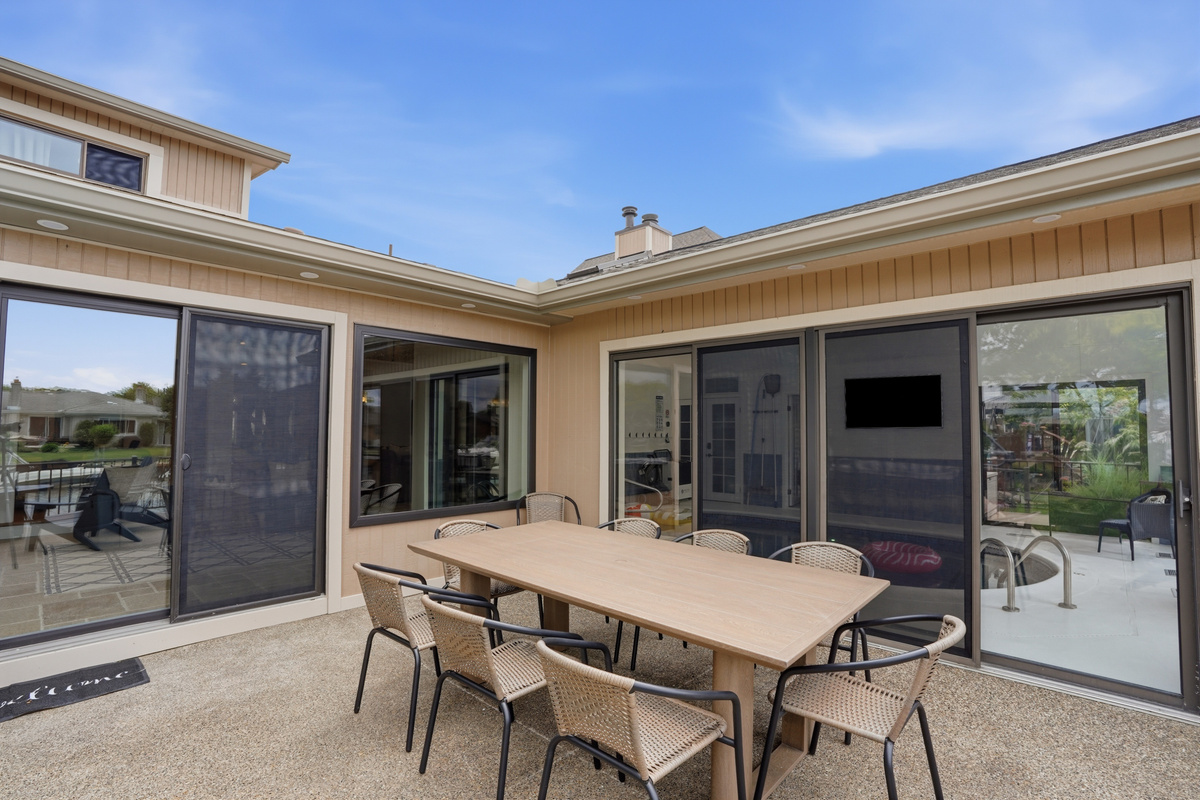 Outdoor patio dining area with a large table, comfortable seating, and seamless indoor-outdoor flow. Bright, spacious setup ideal for entertaining, dining, and relaxing in a private, modern backyard setting.