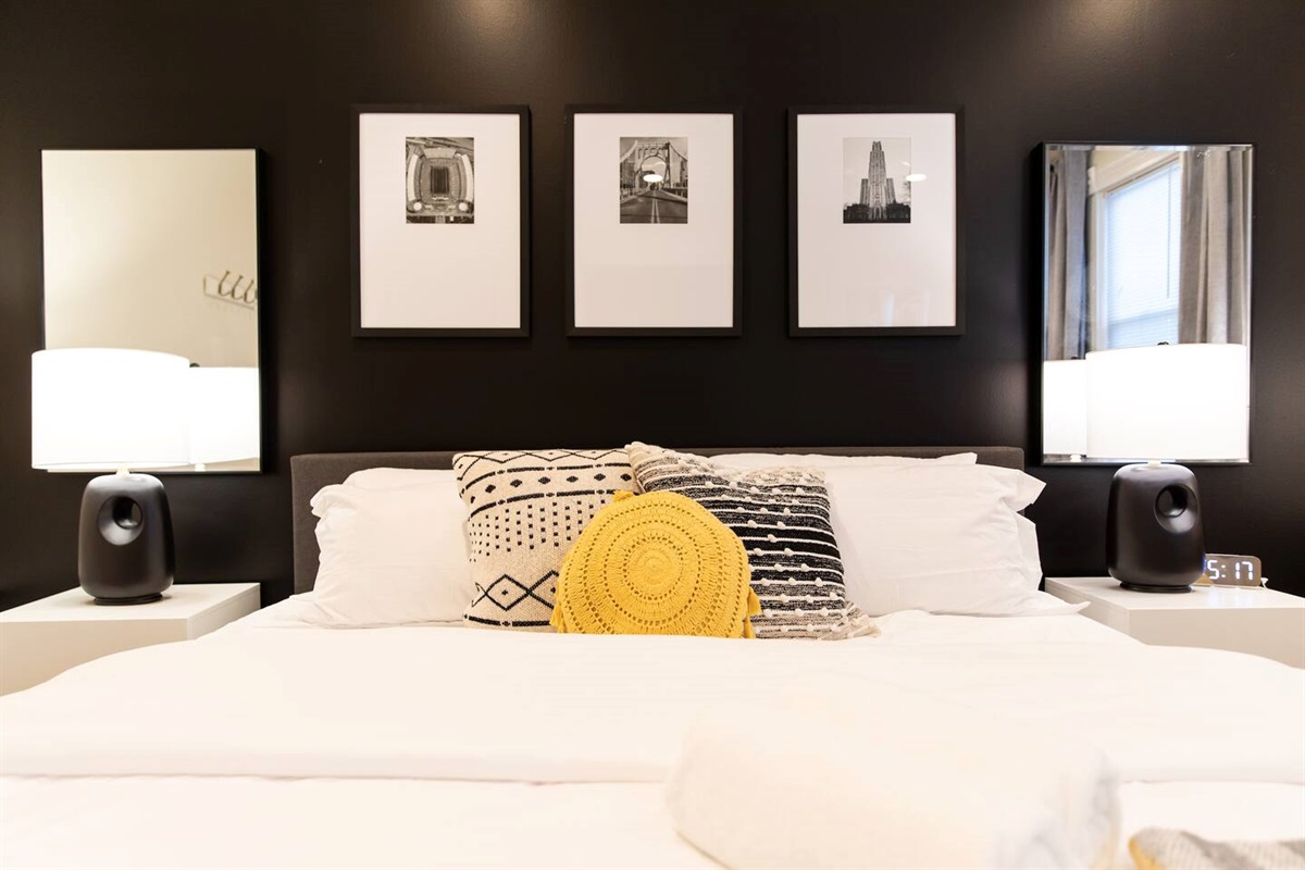 A cozy king-sized bed with soft, inviting linens, positioned beside a large window that lets in natural light, offering a peaceful and serene atmosphere.