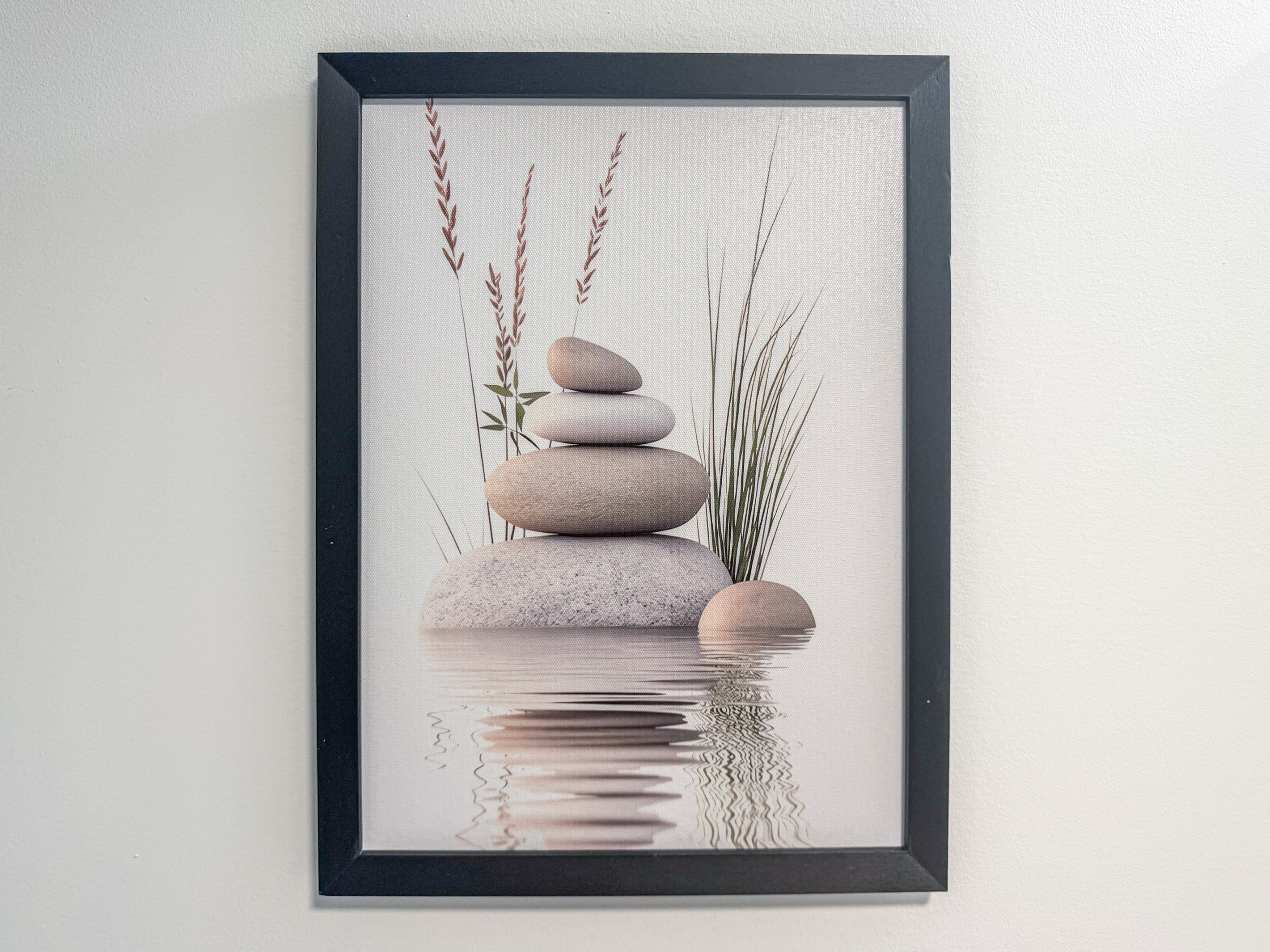 A close-up view details the framed wall art inside the upstairs bathroom, a playful nod to the home's name, "A Stone's Throw." This black-framed print features a balanced stack of zen stones reflecting over calm water against a white wall.