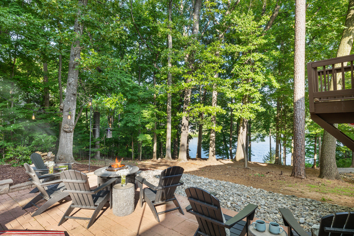 Fire pit surrounded with 6 Polywood chairs with view of a lake