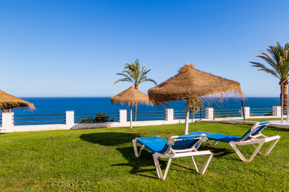 Shared poolside lawn with parasols and sea views