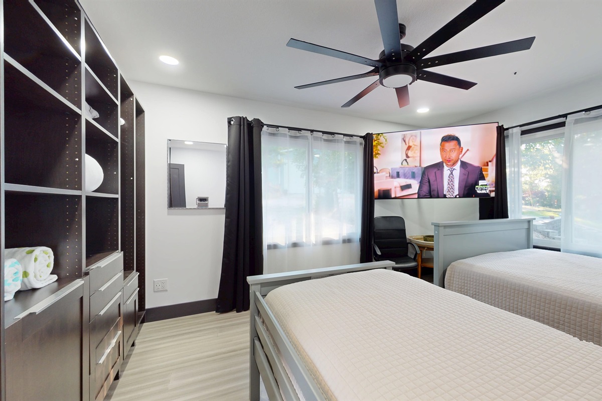 Upper-level bedroom has a full-size bed and a twin bed, a closet system, and large 85" SmartTV