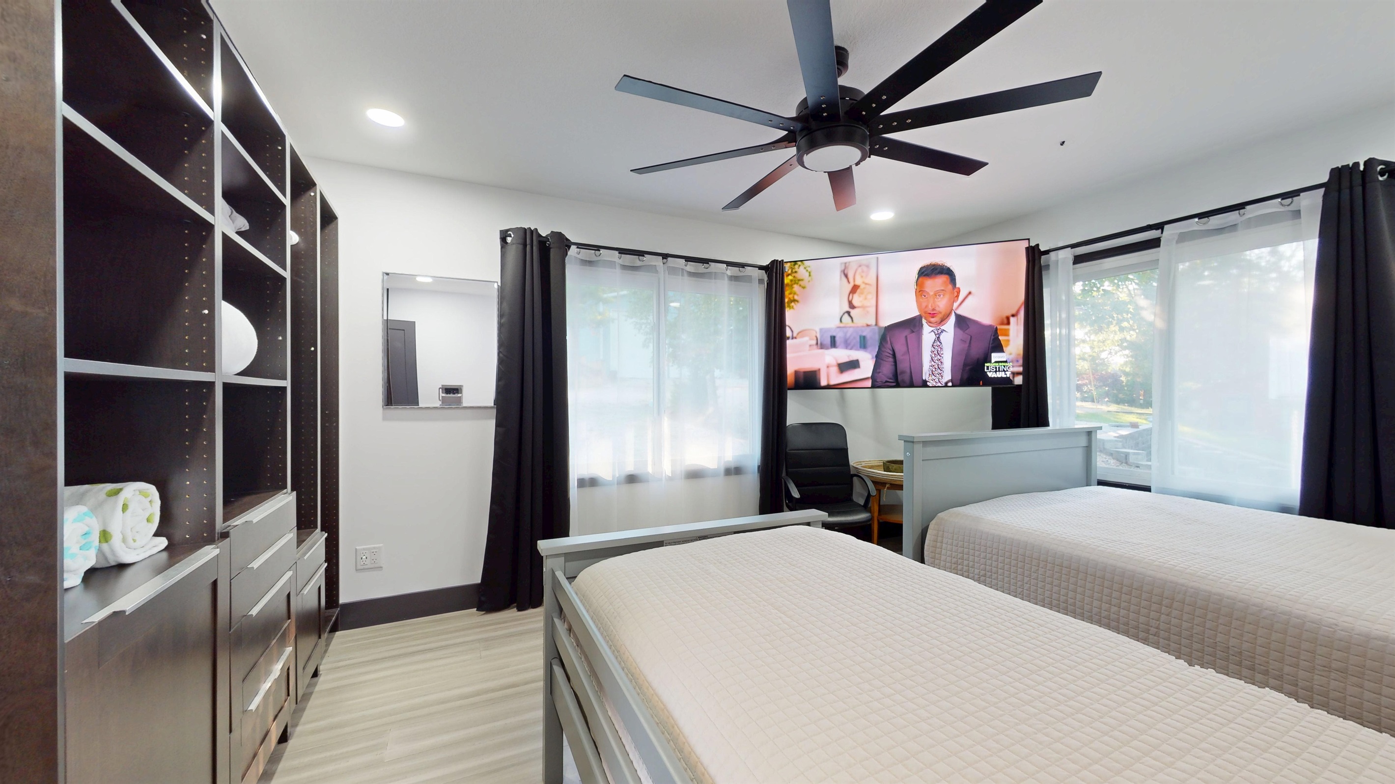 Upper-level bedroom has a full-size bed and a twin bed, a closet system, and large 85" SmartTV