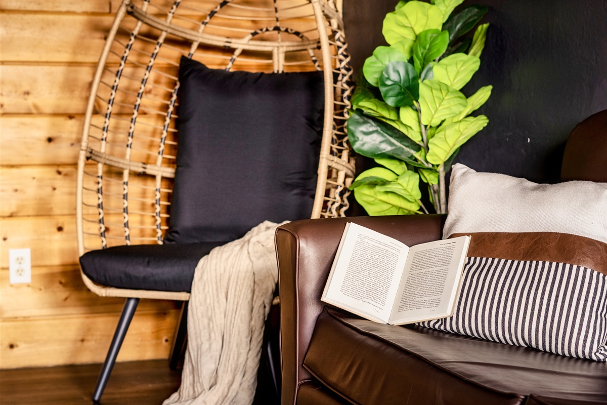 A chair with a book and a plant, sets the space for a peaceful reading and relaxing.