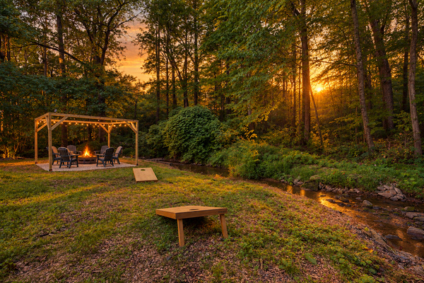 Creekside fire pit under a cedar pergola at dusk in Wears Valley, TN. Fall asleep to the sound of the waterfall