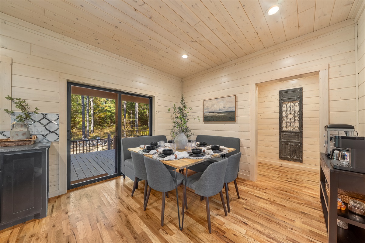 Intimate dining nook with cushioned bench seating and sliding doors that open directly to the forest view deck.