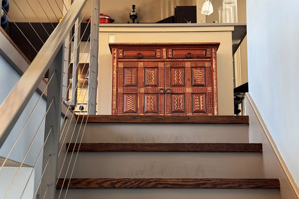 Modern cable-railing stairway leads to the main level social hub. This bright landing features curated designer furniture and offers a first glimpse into the open-concept living, dining, and kitchen areas at the heart of The Crag.