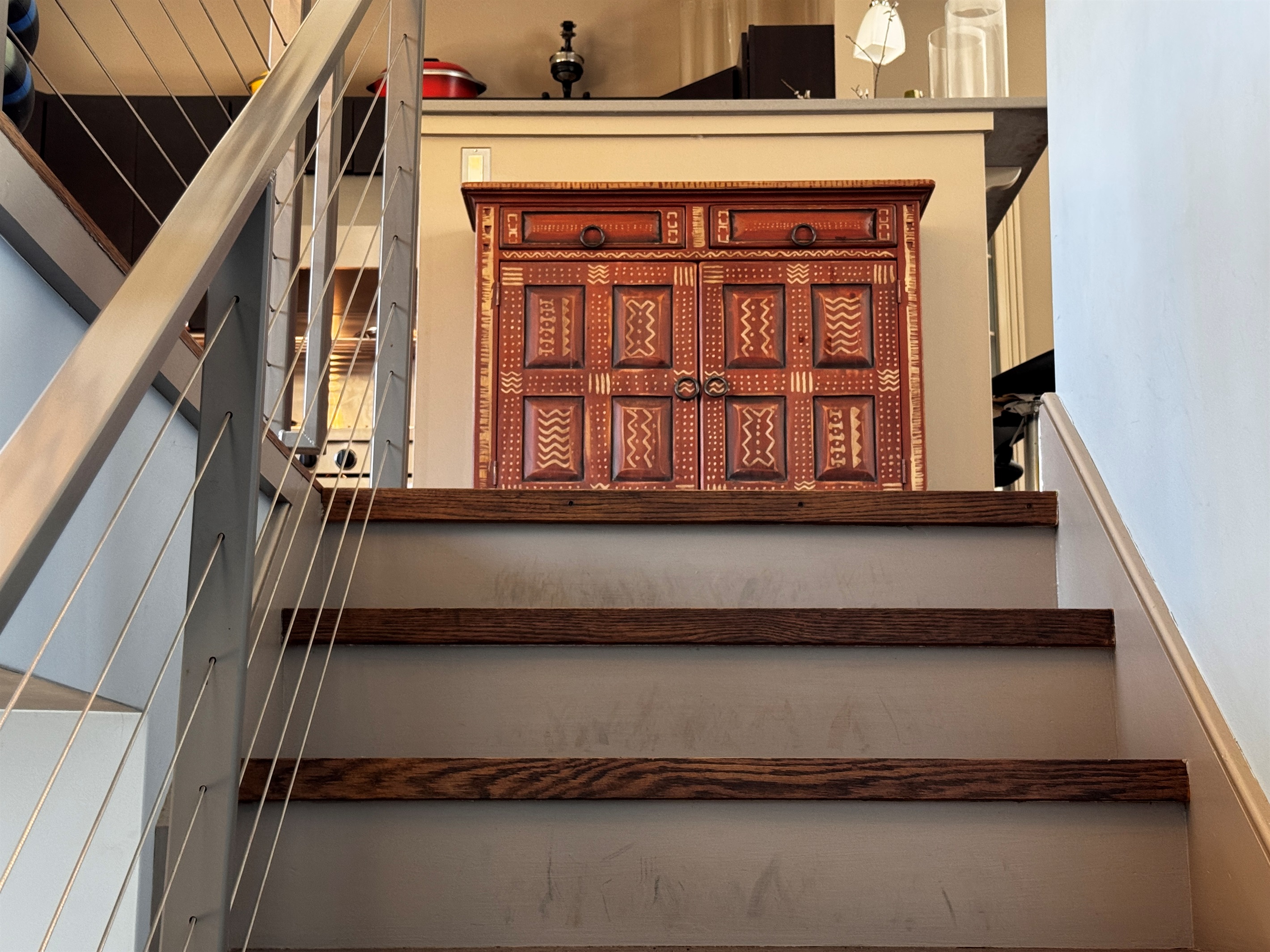 Modern cable-railing stairway leads to the main level social hub. This bright landing features curated designer furniture and offers a first glimpse into the open-concept living, dining, and kitchen areas at the heart of The Crag.