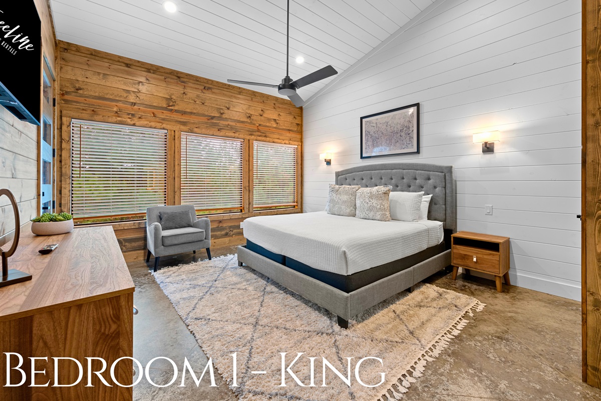 Bedroom 1: King bed with tall windows and natural light.