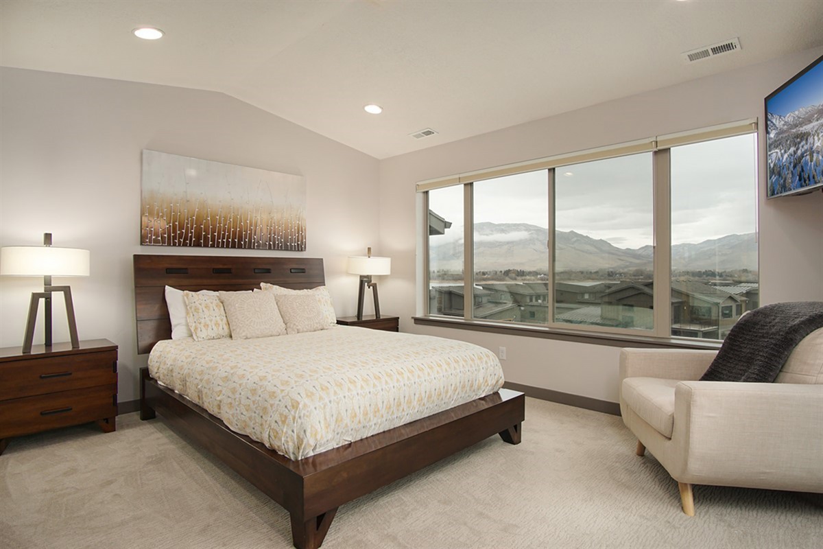 An upstairs primary suite offering expansive mountain views, plush bedding, and a serene ambiance for elevated relaxation.