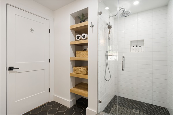 This first floor bathroom is located off the main living area. Featuring a nice walk-in shower enclosure with rain showerhead and a practical shower wand. Open shelving and wicker baskets for additional storage are available.