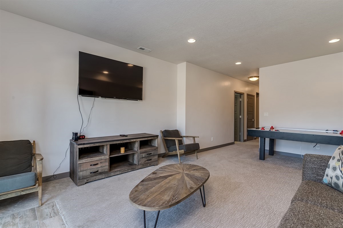 A spacious downstairs rec room designed for relaxation and entertainment, featuring comfortable seating, a large TV, and plenty of room to unwind after a day of adventure.