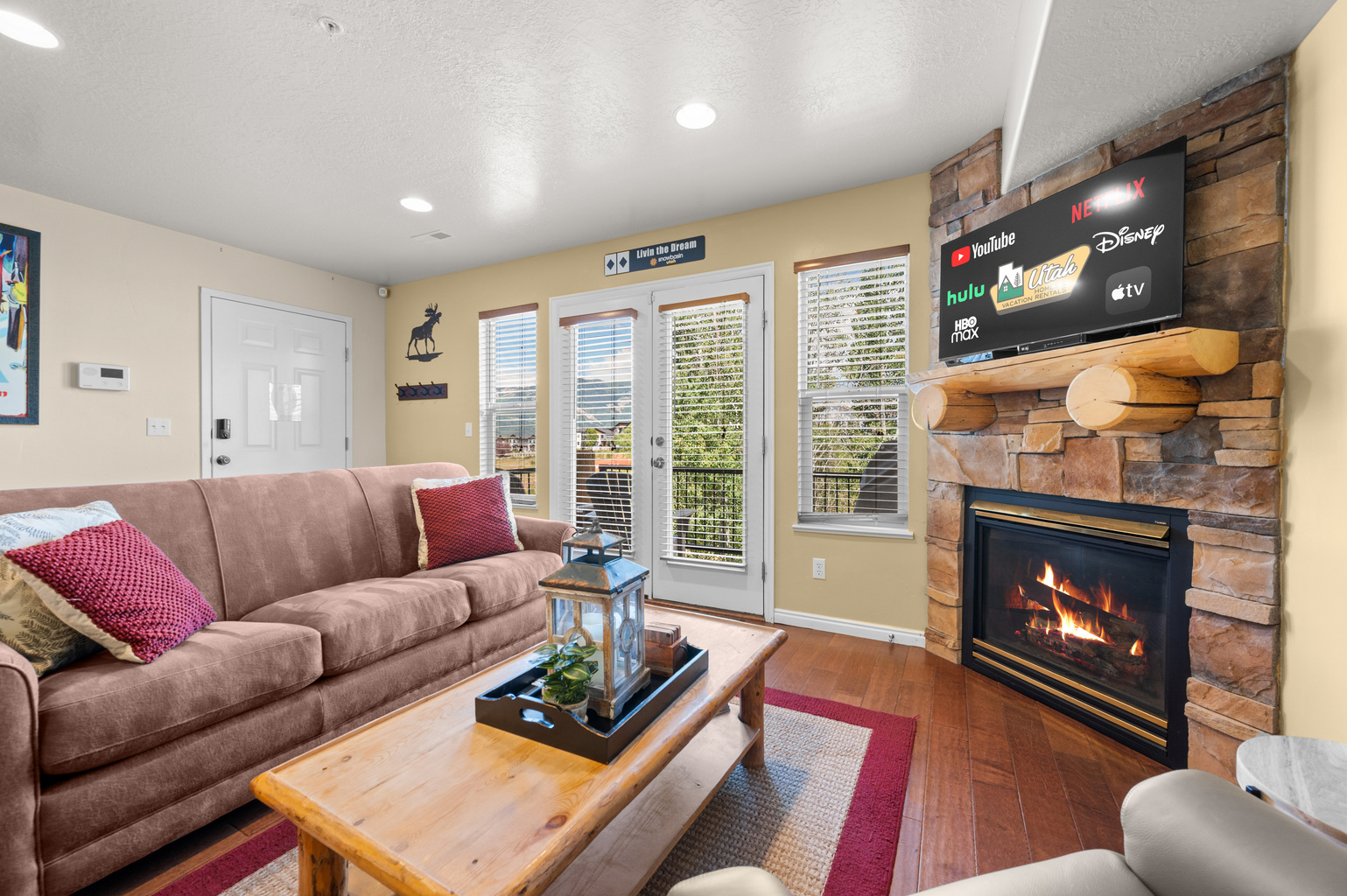 Experience the cozy living room, outfitted with plush seating, a fireplace, an expansive smart TV, and patio doors that frame the breathtaking mountain vistas.