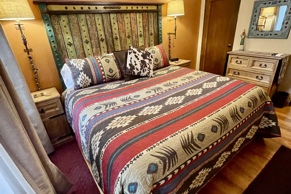 King-size bed with vibrant textiles and artistic accents.