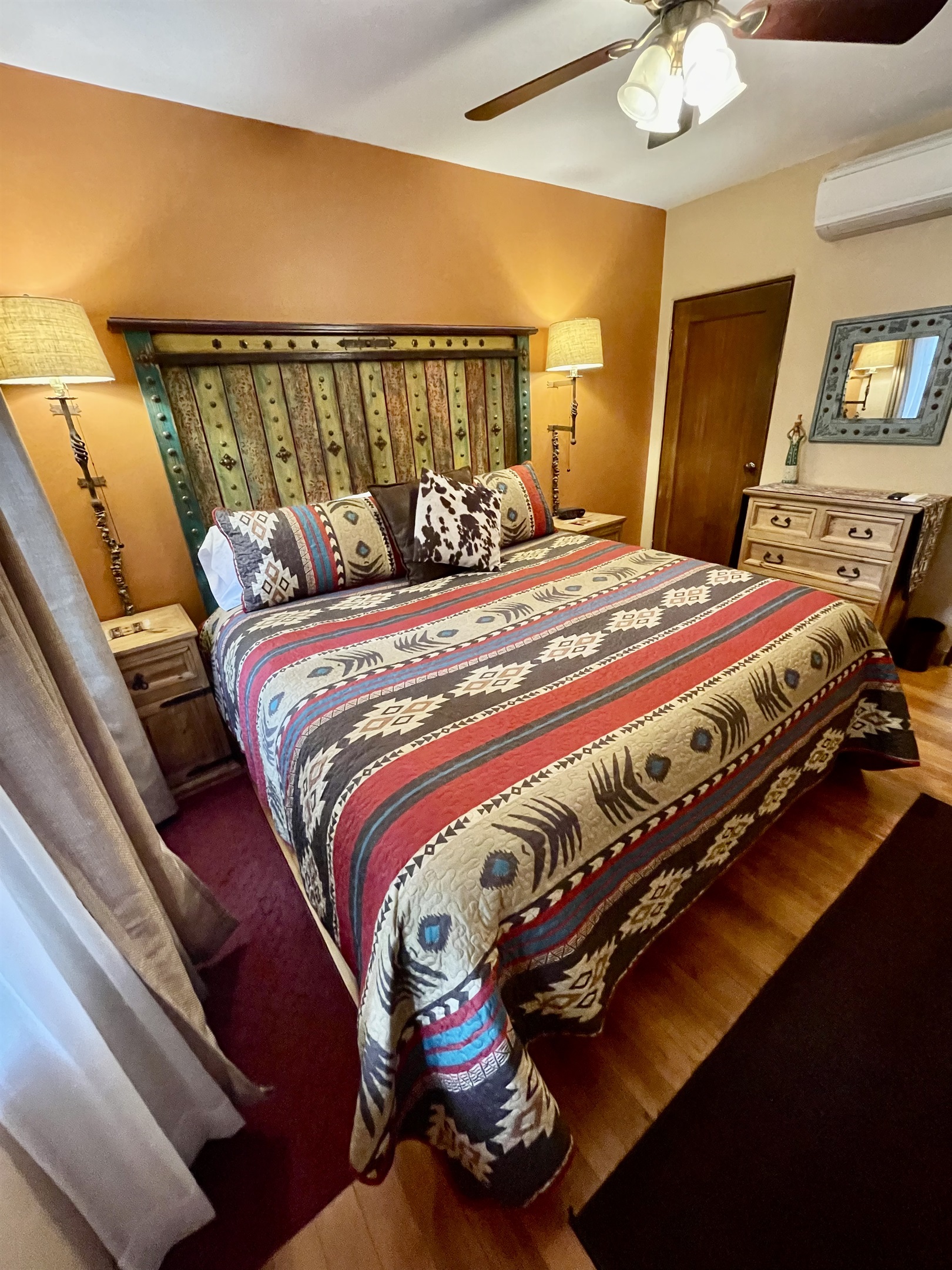 King-size bed with vibrant textiles and artistic accents.