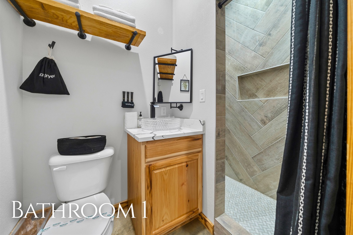 Bathroom 1 includes a spacious shower and warm wood details, creating a relaxing space to refresh and recharge.