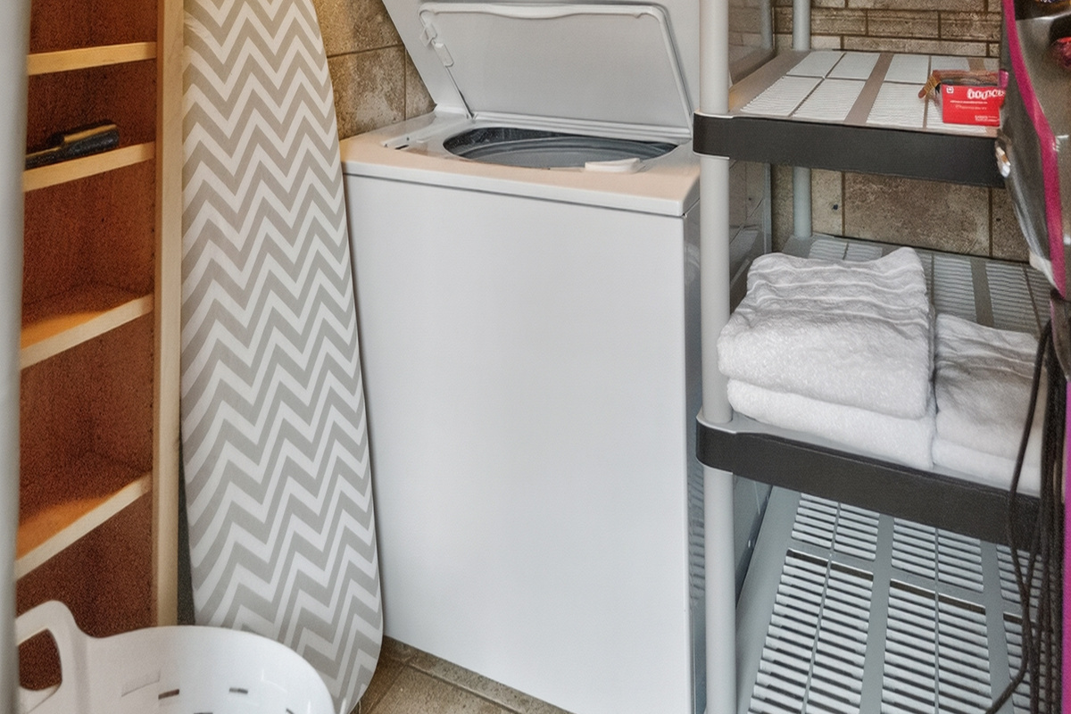 Laundry area with dryer and shelves for folded linens