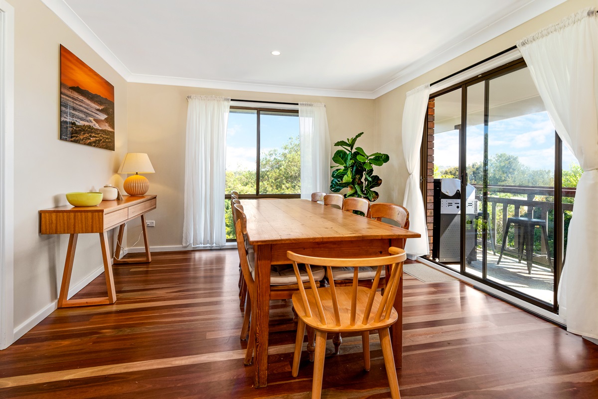 The timber dining table seats 10 beside large sliding doors, giving Bertie’s 3 Beaches a practical shared meal space on the main living level.