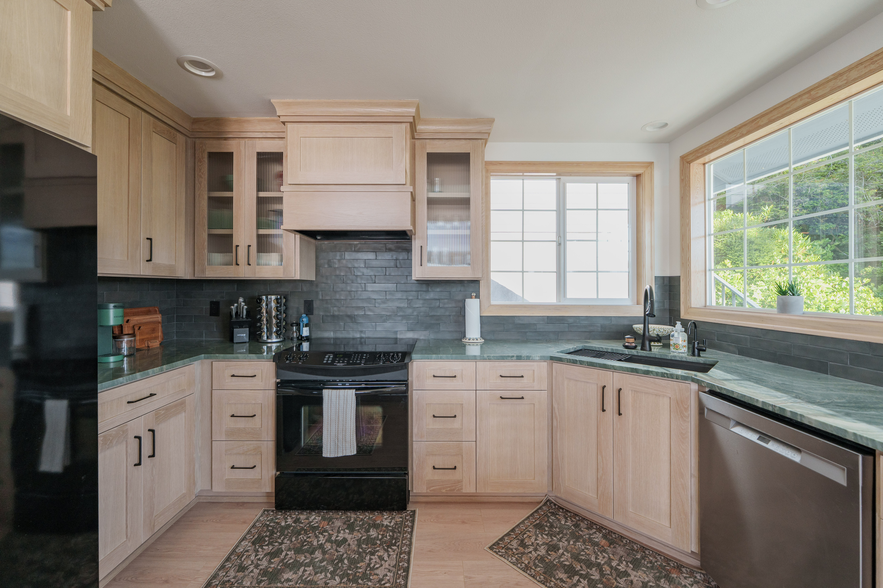 Fully equipped kitchen with modern appliances, generous counter space, and large windows that fill the room with natural light. Coffee station includes Keurig k-cup pods and traditional ground coffee maker