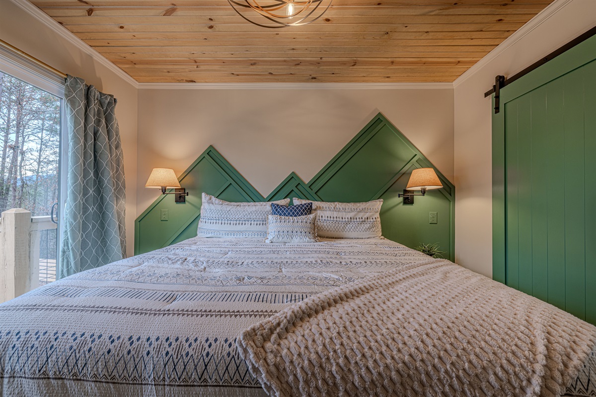 Retreat to a primary suite where rustic charm meets modern style. The natural wood ceiling and mountain headboard create the ultimate cabin sanctuary.