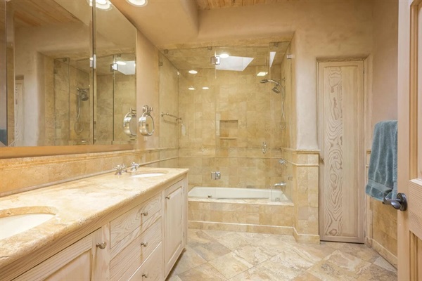 Primary bathroom with double vanity and enclosed tub/shower.