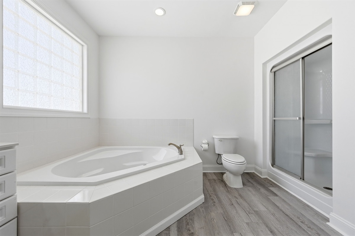 Bright and airy ensuite bathroom with a large soaking tub and separate glass-door shower