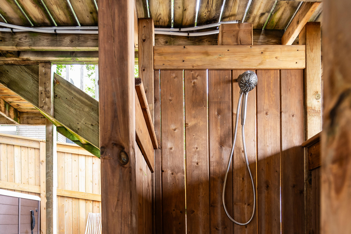 Rustic outdoor shower with natural wood walls and traditional fixtures.