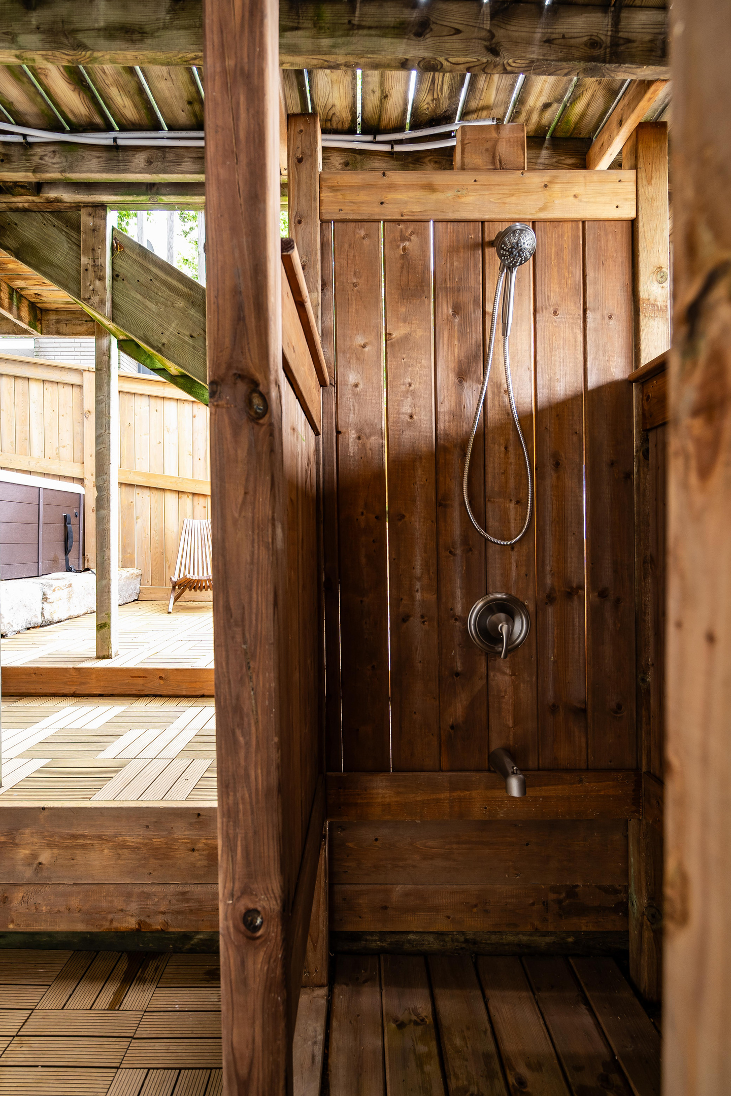 Rustic outdoor shower with natural wood walls and traditional fixtures.