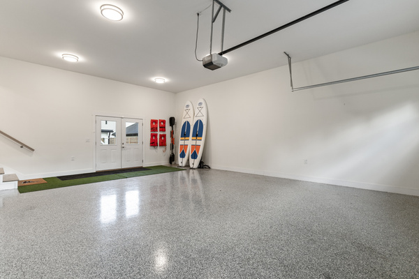 Garage with storage for paddle boards, paddles and life jackets, and double wide doorway that leads to the backyard.