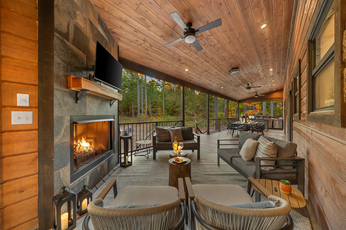 Outdoor lounge with plush seating, a stone fireplace, and TV, designed for cozy movie nights in the fresh mountain air.