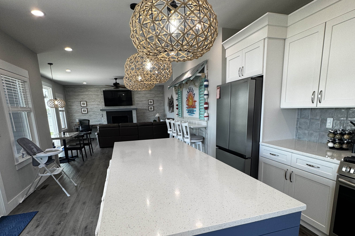 Modern kitchen with a large island, stylish pendant lighting, stainless steel appliances, and open layout flowing into the living and dining areas—perfect for cooking, dining, and entertaining.