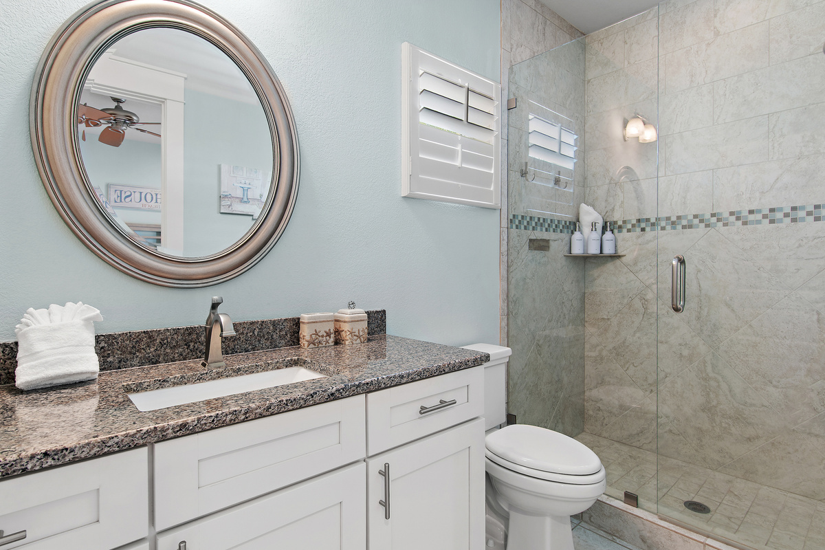 Bright, spacious bathroom with a walk in shower, generous vanity, and elegant coastal details.
