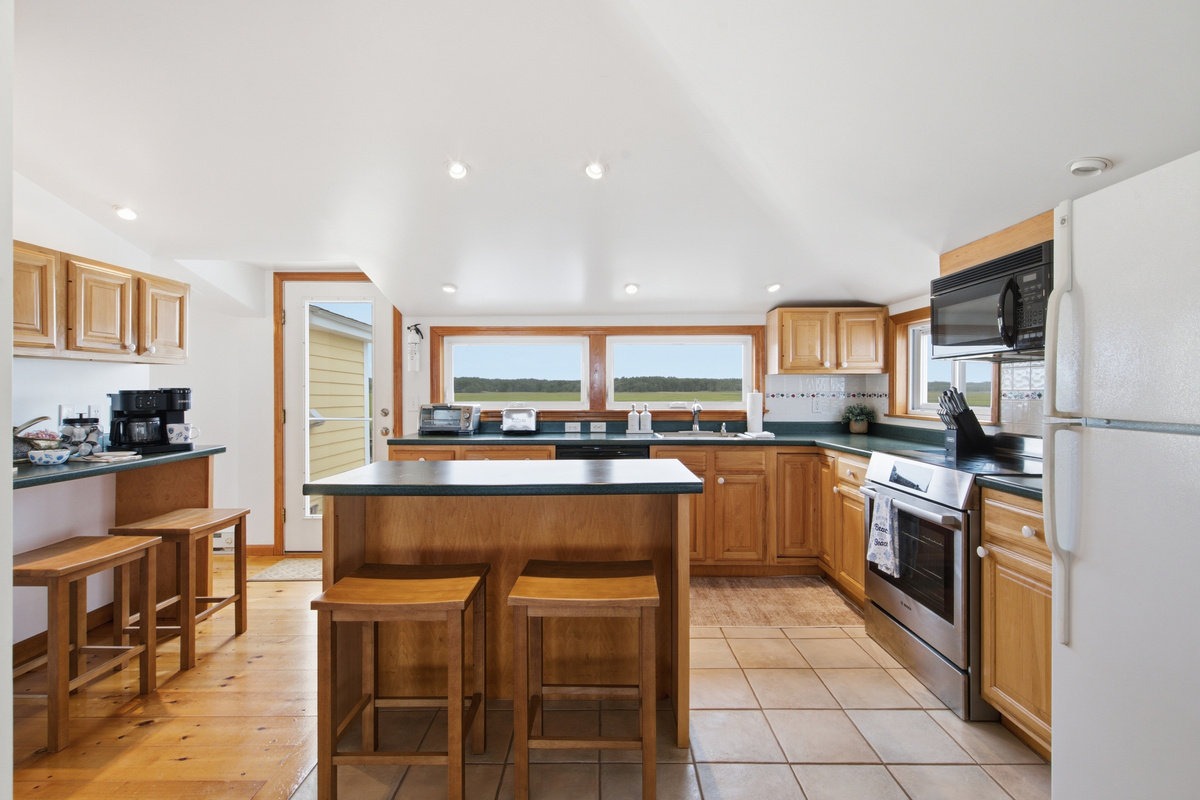 Fully equipped kitchen with an island, bar seating, and scenic marsh views.