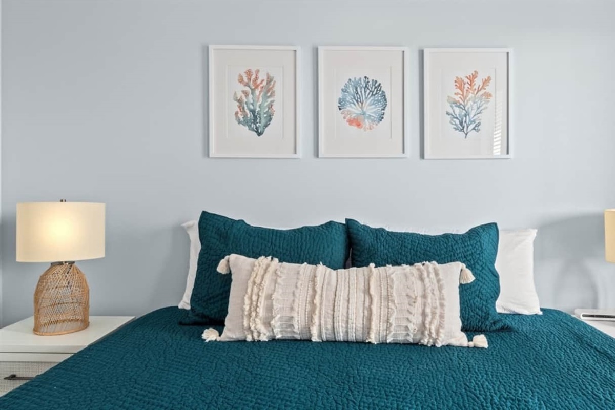 Sink into deep teal bedding under soft coastal art.