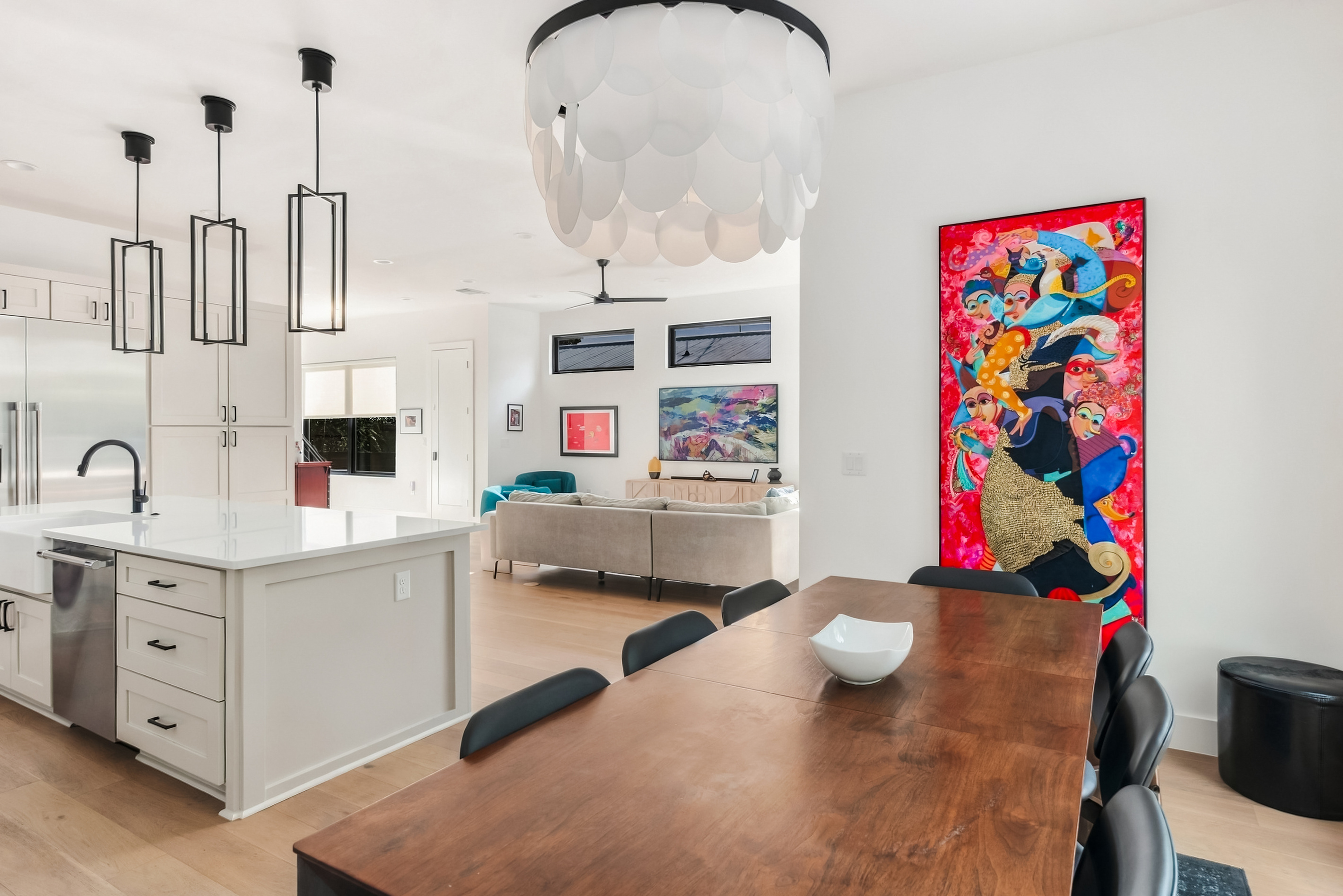 Open-concept dining flows into the kitchen, anchored by bold statement art.