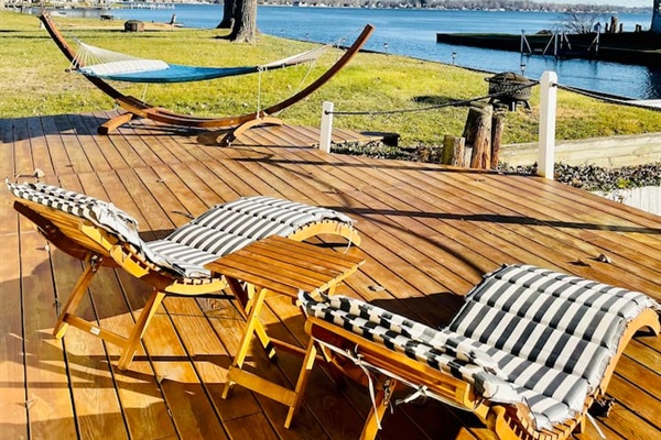 Large lakeside deck with lounge chairs overlooking the water.